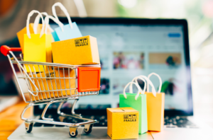 Shopping cart with bags inside of it in front of laptop