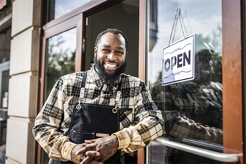 Happy, young black man outside of his business